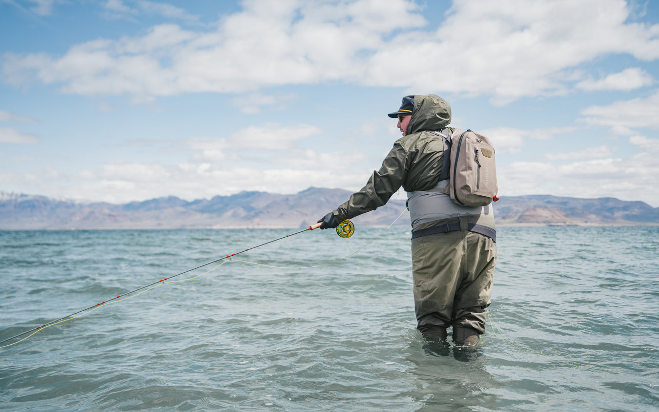 An man is standing in knee high water and fly fishing